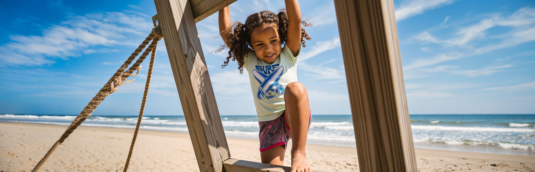 Image of Child playing on a swing at the beach with ocean and sky in the background