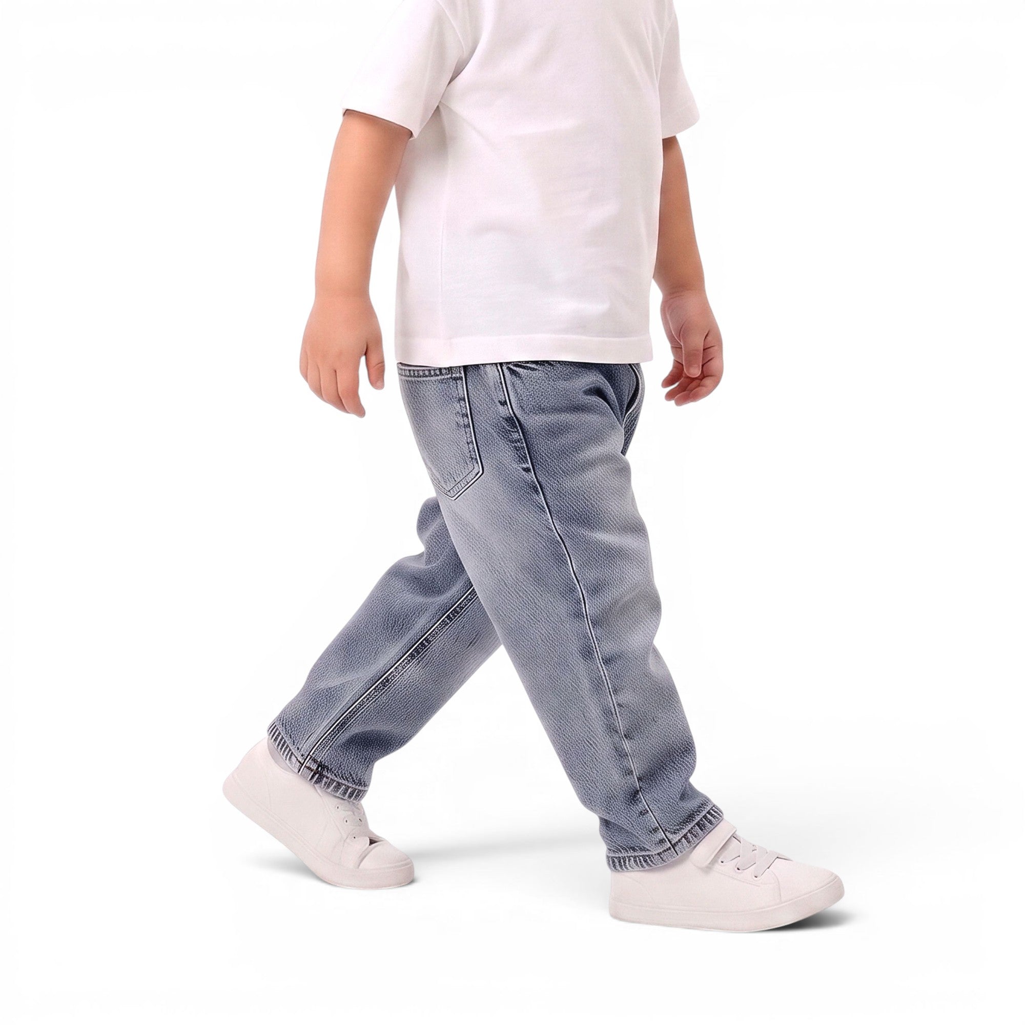 A child wearing light-wash blue denim jeans, a white t-shirt, and white sneakers, captured from a side profile against a clean white studio background.